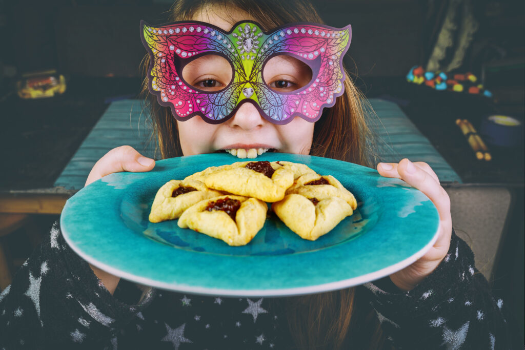 Girl wearing mask with plate of hamantashen - Purim